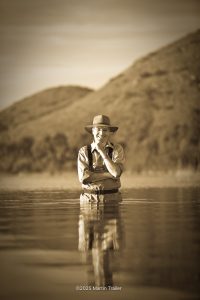 man standing in lake wearing waders