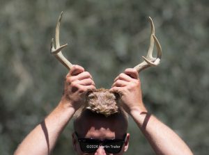 man holding six point deer antlers over his head