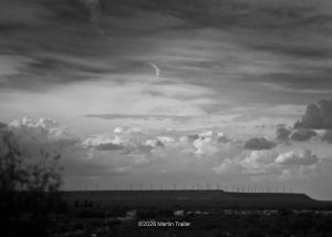 distant view of wind machines on a bluff with big puffy clouds